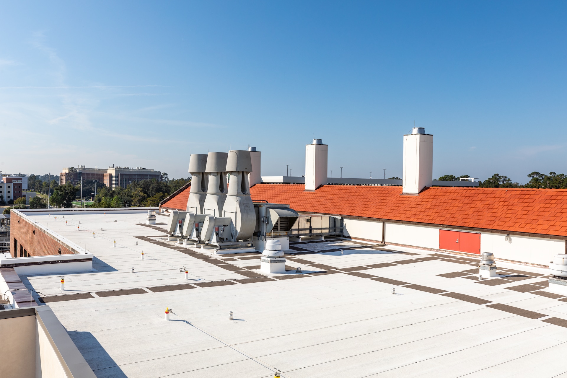 Aerial view of a commercial flat roof assembly showing parapet walls, HVAC equipment, and roof membrane detailing.